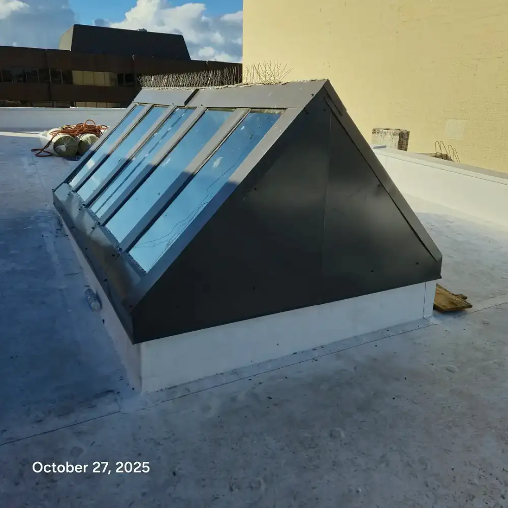 Pyramid-shaped glass skylight set into a rooftop, surrounded by concrete. October 27, 2025.